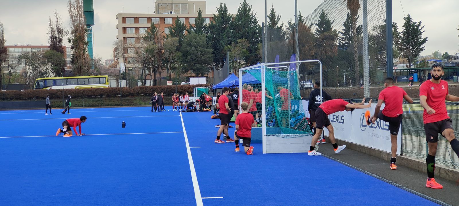 Jugadores de hockey césped haciendo elongación en una cancha azul
